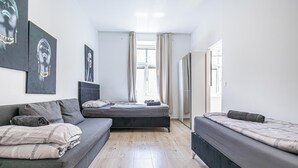 Een moderne slaapkamer met een slaapbank, een enkel bed en een groot raam met gordijnen.