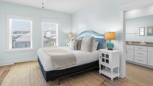 A bedroom with a bed, bedside lamps, a nightstand, a ceiling fan, and a view of the outside. - 30A Stay • Golf Cart, Bikes, Outdoor Lounge + Near Beach | Constant Getaway (Santa Rosa Beach)