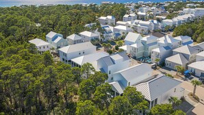 A coastal residential area with modern houses, dense greenery, and a clear view of the ocean. - 30A Stay • Golf Cart, Bikes, Outdoor Lounge + Near Beach | Constant Getaway (Santa Rosa Beach)