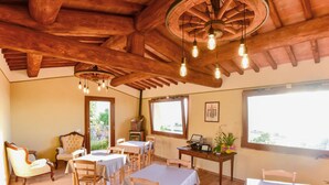Un espace repas agrémenté de poutres en bois, de tables recouvertes de nappes blanches et de chaises.
