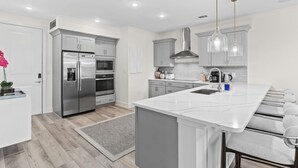 Una cocina moderna con una isla grande, electrodomésticos de acero inoxidable e iluminación colgante.