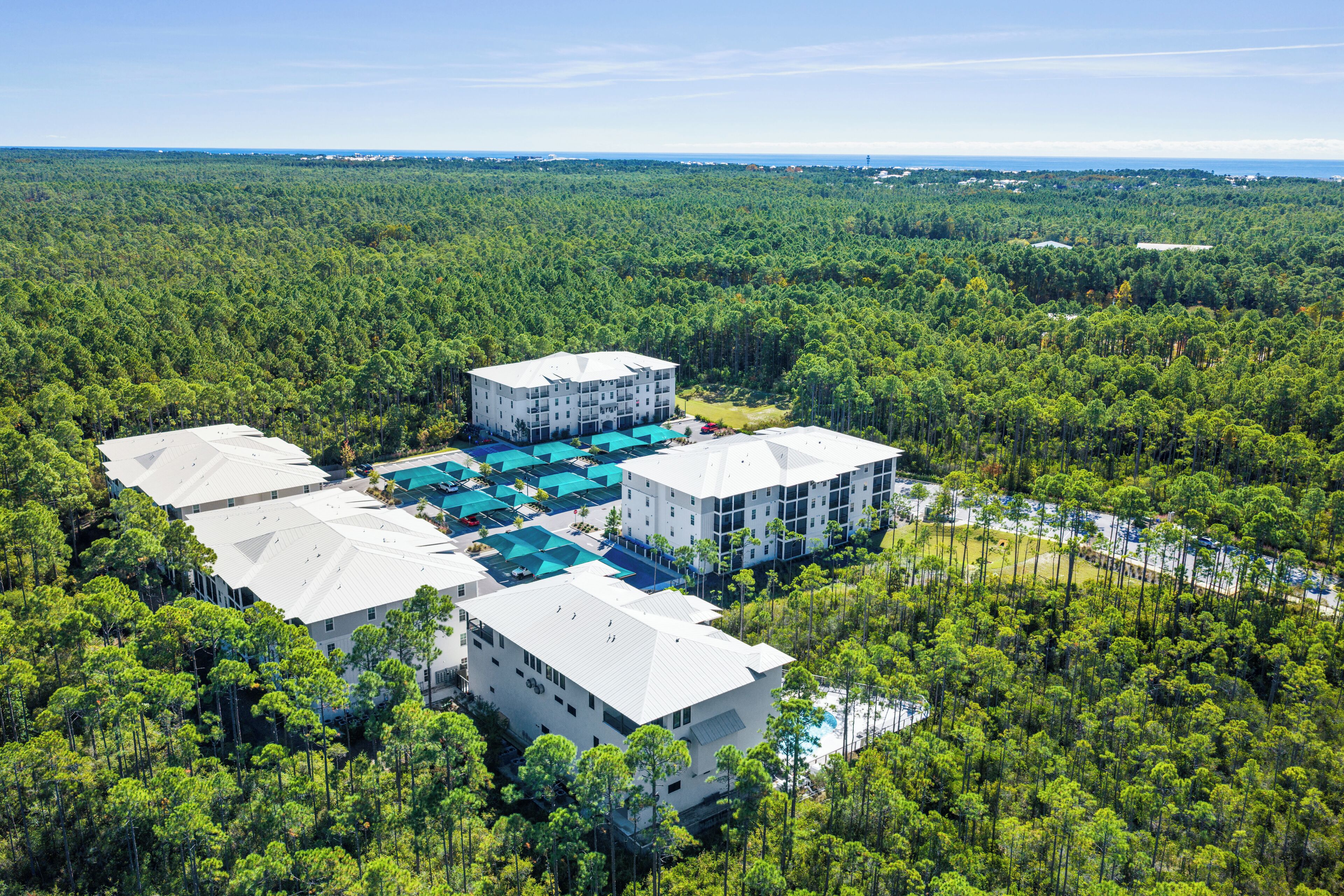 Vue aérienne d’un complexe hôtelier composé de plusieurs bâtiments, entouré d’une forêt dense.