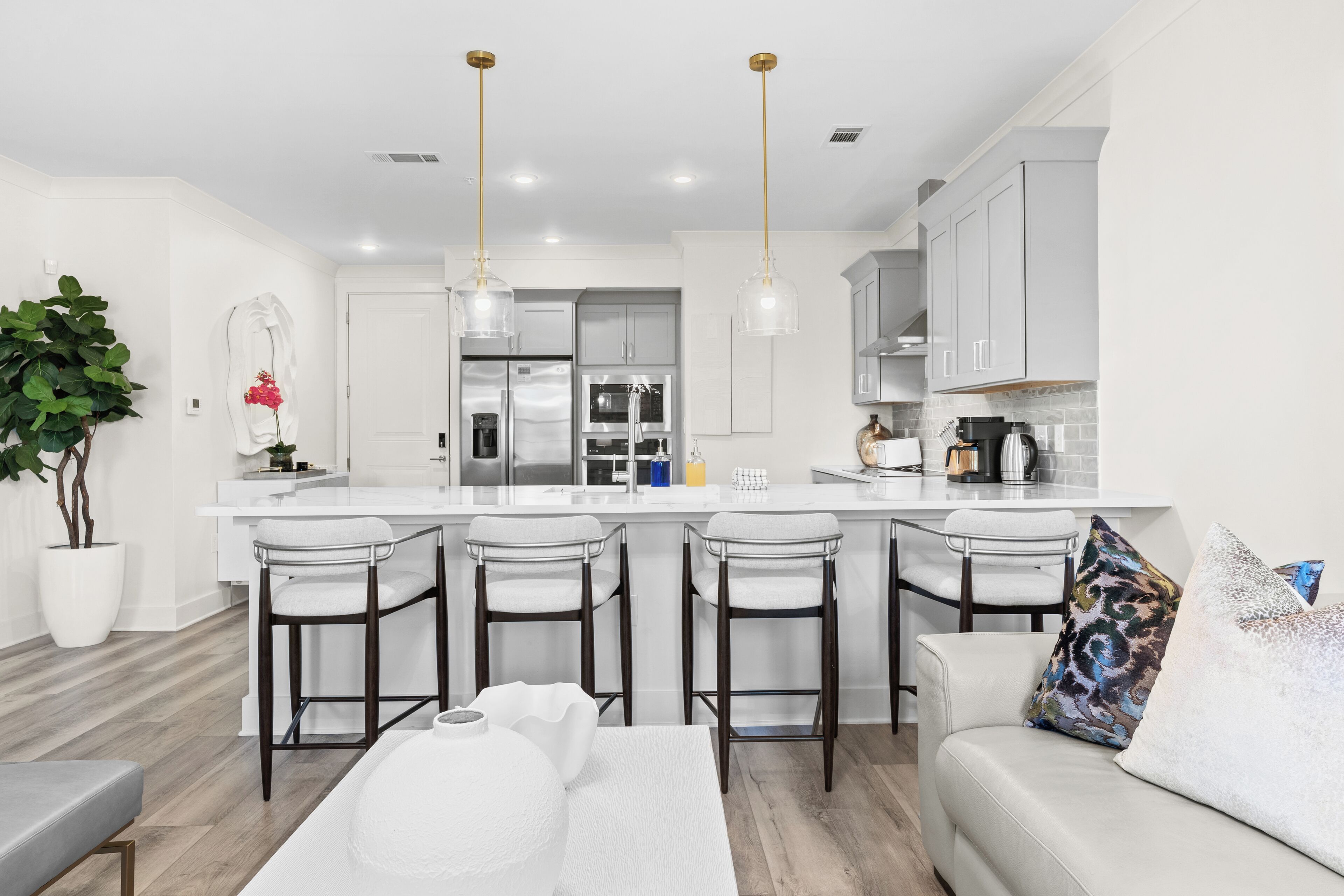 A modern kitchen with white cabinetry, a central island with bar stools, and pendant lighting.