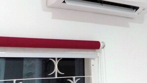 A white air conditioning unit mounted on a wall. - Penginapan Rumah Kuning Syariah (Bogor)