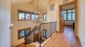 A spacious interior with a wooden staircase, a chandelier, and large windows allowing natural light. - Truckee Escape w/ Hot Tub, Chef’s Kitchen & Minutes to Skiing, Dining & Trails (Truckee)