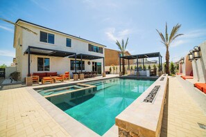 Een modern huis met een zwembad, buitenzitplaatsen en een overdekte patio.