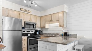 Eine moderne Küche mit Holzausstattung, Edelstahlgeräten und einer Arbeitsplatte aus Granit.