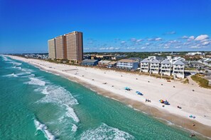 A beachfront hotel with multiple buildings, a sandy beach, and ocean waves. - Steps to the Beach | Pool, Tennis, & Putting Green | Southwinds H12 by AvantStay (Panama City Beach)