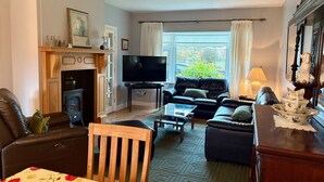 A living room with a fireplace, a television, a sofa, and a dining area.