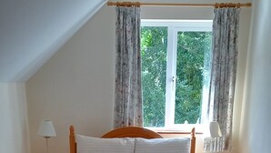A bedroom with a bed, two nightstands, a window with curtains, and a view of greenery outside. - Birchview Lodge Kenmare (Kenmare)