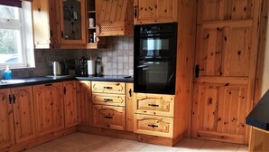 A kitchen with wooden cabinets, a black oven, and a window. - Birchview Lodge Kenmare (Kenmare)