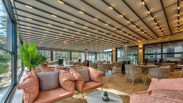 A spacious indoor area with multiple seating arrangements, including sofas and tables, under a ceiling with linear lighting fixtures. - Zlatibor Deluxe Suites with Spa Fitness (Zlatibor)