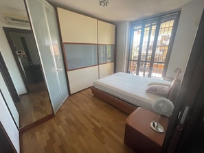Ein Schlafzimmer mit Bett, Kleiderschrank, Nachttisch und einem Fenster mit Blick.