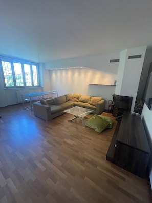 Ein großzügiger Wohnbereich mit Ecksofa, Glastisch und Kamin.