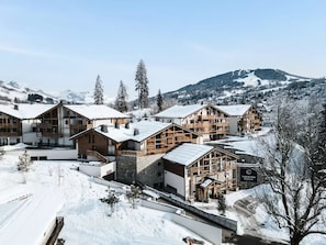 Eine schneebedeckte Lodge mit Holzhütten, einer Seilbahn und einer Bergkulisse.