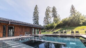 Un edificio moderno con piscina, rivestimento in legno e area salotto esterna.