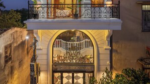 Un immeuble de deux étages doté d’un balcon, d’une entrée décorative et d’une façade bien éclairée.