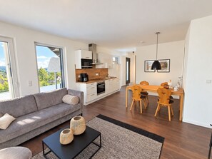 A modern living room with a sofa, coffee table, and dining area with chairs and a table.