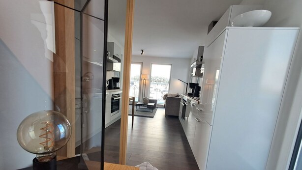 A modern kitchen with white cabinets, a wooden countertop, and a large window. - Modern vacation apartment with exceptional views and its own infrared cabin (Winterberg)