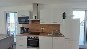 A modern kitchen with white cabinets, a built-in oven, a microwave, and a sink. - Modern vacation apartment with exceptional views and its own infrared cabin (Winterberg)