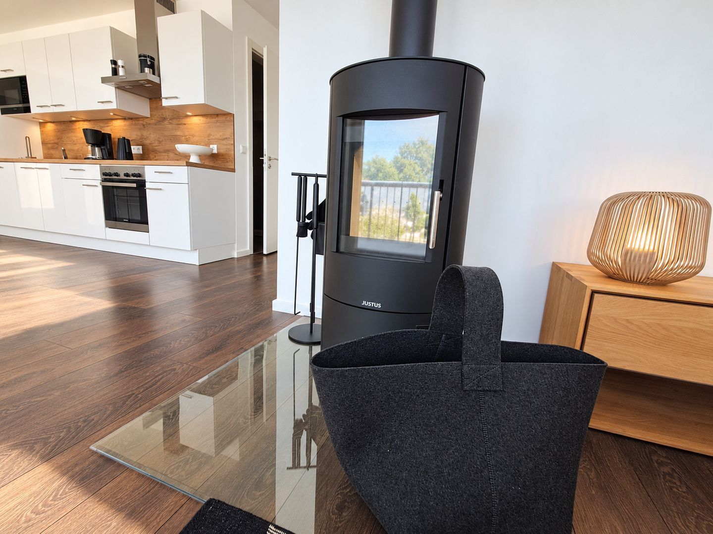 A modern kitchen with white cabinets, a black stove, and a glass-top dining table.