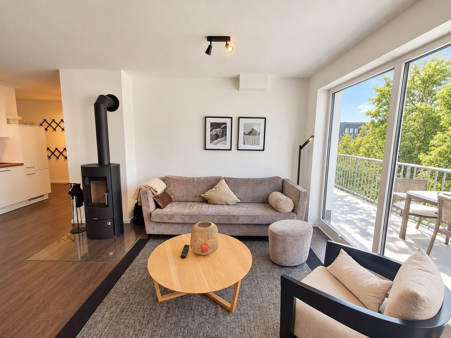 Una sala de estar moderna con un sofá, una mesa redonda de centro, una chimenea y un balcón con mobiliario exterior.