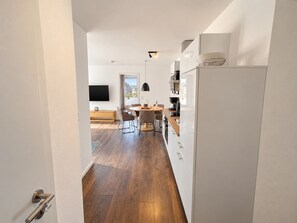 A modern kitchen with a dining area, wooden flooring, and a large window.