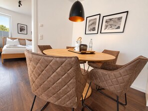 A modern dining area with a round wooden table, quilted chairs, and a pendant light. - Modern lodge with exceptional countryside views and private sauna - (Winterberg)