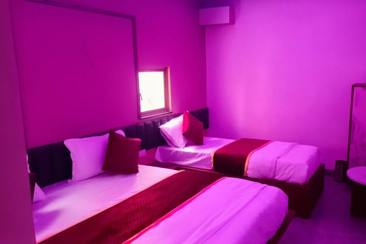 A room with two beds, a window, a mirror, and a small table.