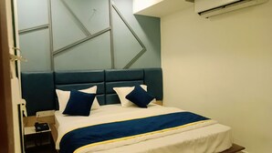 Een hotelkamer met een bed, een bureau met telefoon en een wandairconditioner.