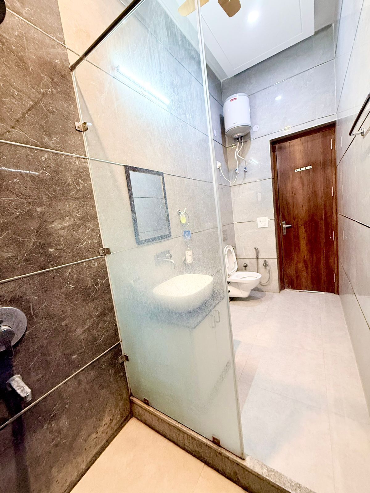 A modern bathroom with a glass shower enclosure, a sink, and a toilet.