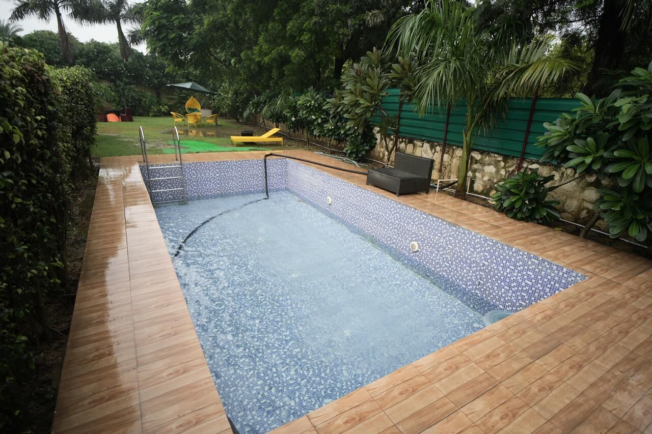 A rectangular swimming pool with a tiled edge, surrounded by a wooden deck.