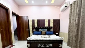 A bedroom with a bed, a ceiling fan, and an air conditioning unit. - Mango People Farm (Sohna)