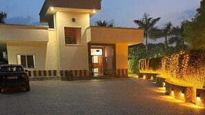 A modern building with a car parked in front. - Mango People Farm (Sohna)