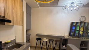 Une cuisine moderne avec des meubles en bois, un évier en acier inoxydable et un coin bar équipé de tabourets.