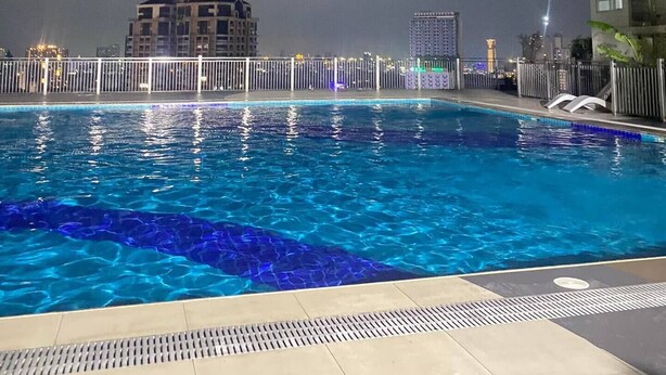 Une piscine dotée d’une terrasse carrelée, entourée d’une clôture blanche.