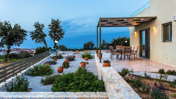 A rooftop terrace with a pool, outdoor seating, and a stone retaining wall. - Villa Iokasti with heated pool (Rethymno)