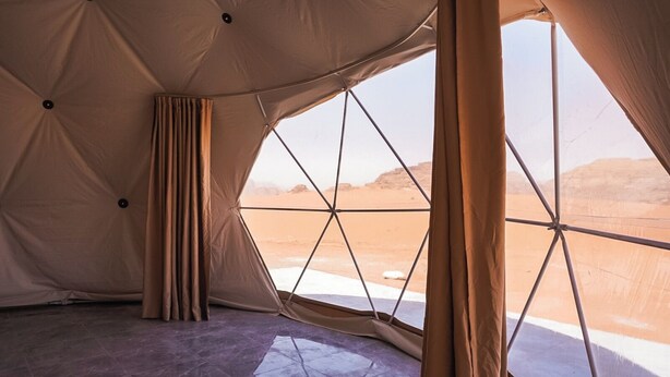 A tent with a geometric window design, providing a view of a desert landscape. - Shaheen Camp Wadi Rum – Deluxe Tent (العقبه)
