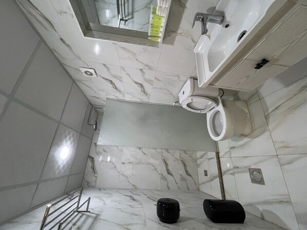 Une salle de bain comprenant des toilettes, un lavabo et un espace douche.