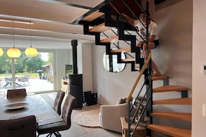 A modern interior with a spiral staircase, a dining area with a table and chairs, and a large window providing a view of the outdoors. - Peaceful holiday home near Hannut (Hannut)