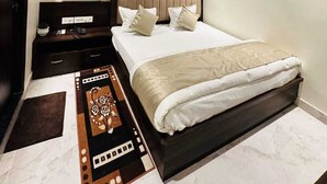 A modern bedroom with a large bed, a bedside table with a phone, and a decorative rug. - Kashi Darshan Hotel (Varanasi)