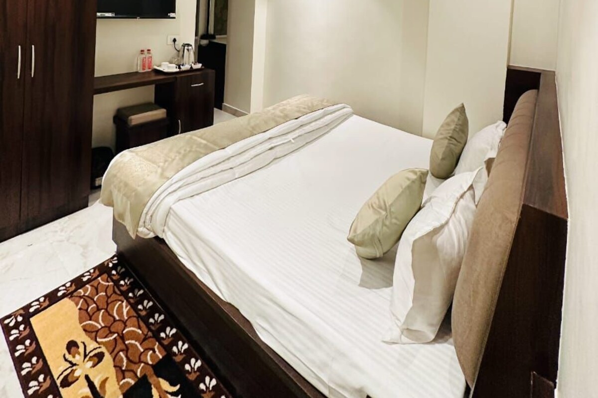 Una camera da letto moderna con un letto grande, una ventola a soffitto, un armadio in legno scuro, un comodino e uno specchio.