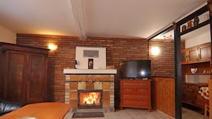 Una sala de estar con chimenea de ladrillo, muebles de madera y un televisor.