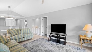 Ein modernes Wohnzimmer mit Sofa, Fernseher und Deckenventilator.