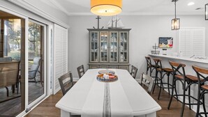 Un comedor con una mesa larga, sillas y una isla central con una bandeja.