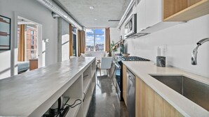 Una cocina moderna con una isla grande, electrodomésticos de acero inoxidable y vistas al exterior.