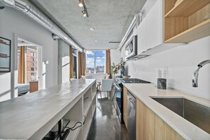 Eine moderne Küche mit einer großen Kochinsel, Edelstahlgeräten und Blick ins Freie.