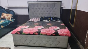 Un dormitorio con un cabecero capitonado, una cama con colcha floral y una mesita de noche con lámpara.