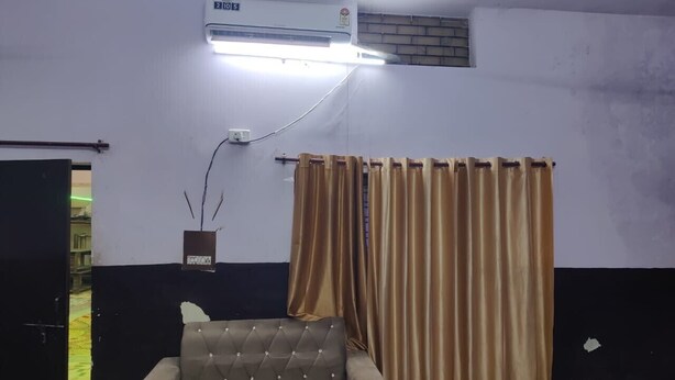 Una habitación con un sofá, aire acondicionado de pared y una cortina.