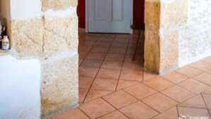 Una entrada con arco de piedra que conduce a un espacio con una puerta roja y un letrero encima.